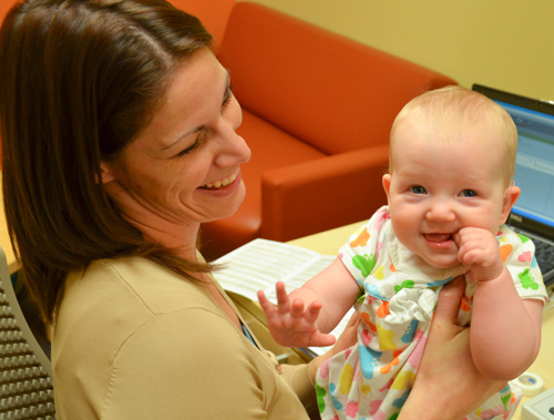 a smiling audiologist holding a smiling baby