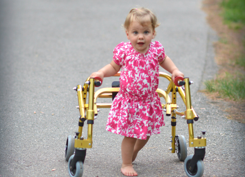 a toddler walking down the sidewalk with a walker